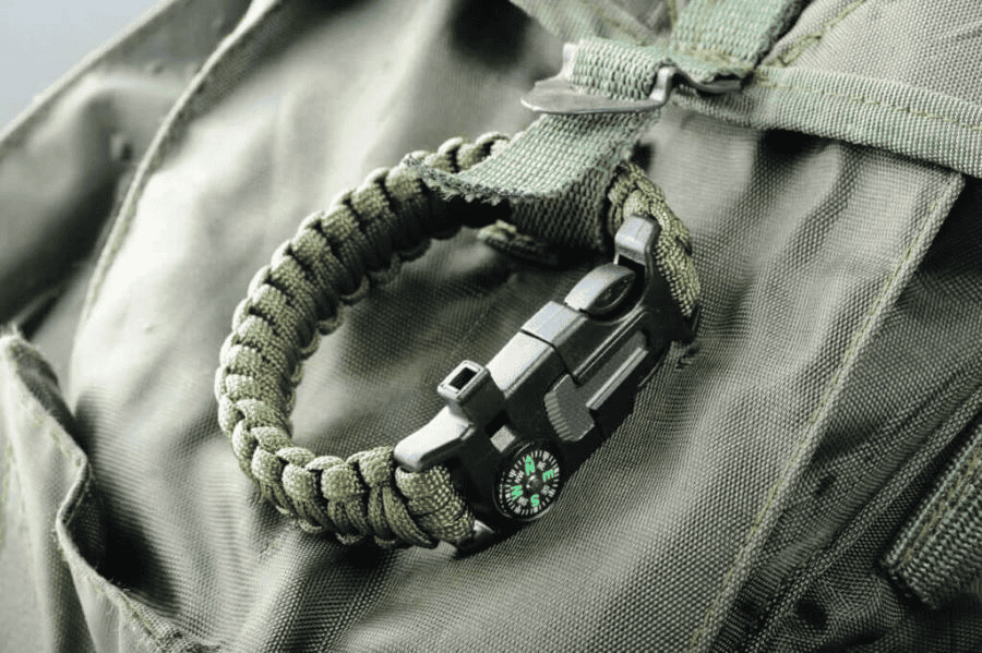 Paracord manufacturer: Green paracord survival bracelet attached to a backpack.