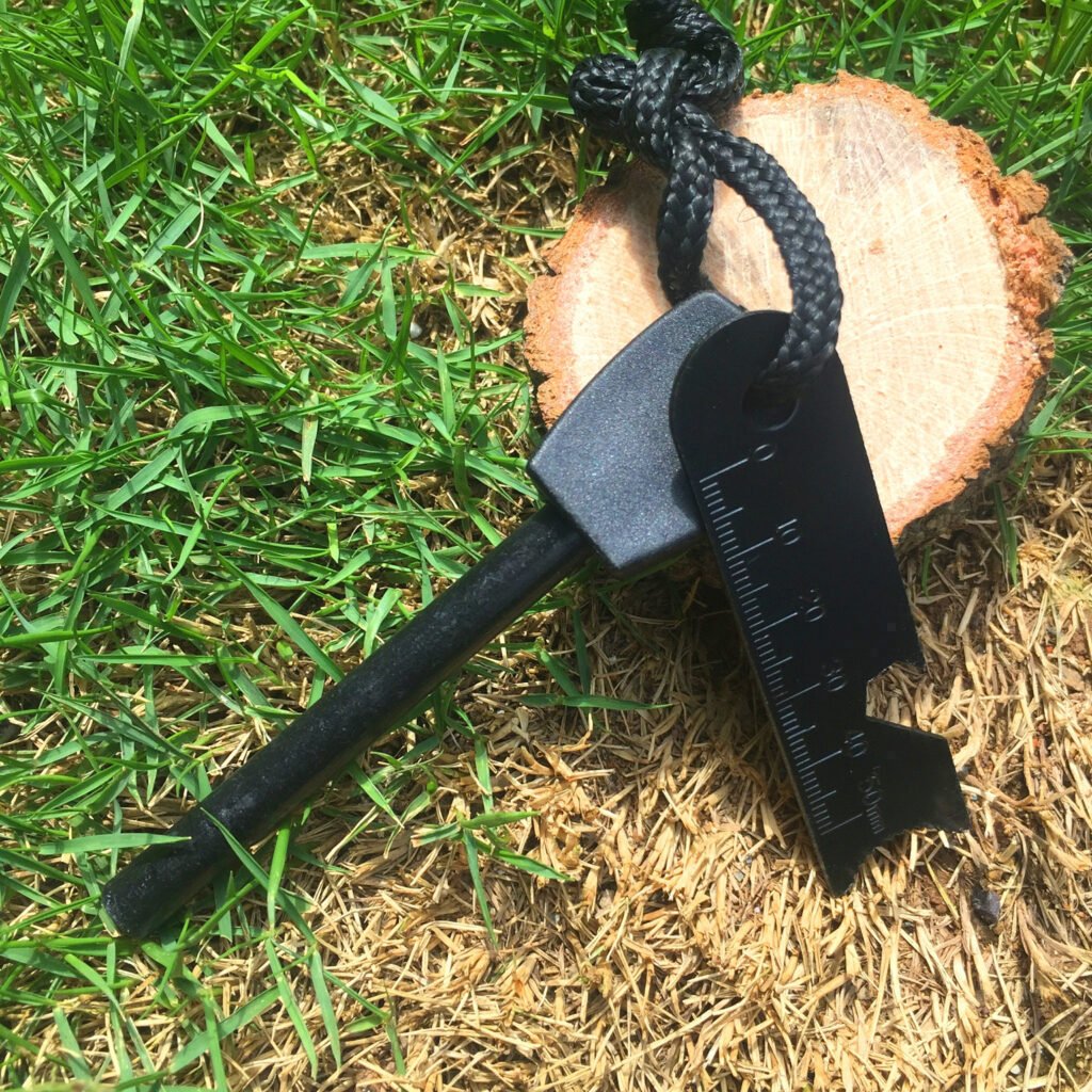 Premium bulk fire steel fire starter featuring a textured black ergonomic handle and a tactical multi-tool steel scraper connected by a paracord lanyard.