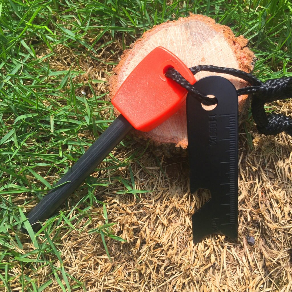 High-visibility orange handled bulk fire steel kit showcasing a multi-functional black pocket scraper with a ruler and bottle opener for survival use.