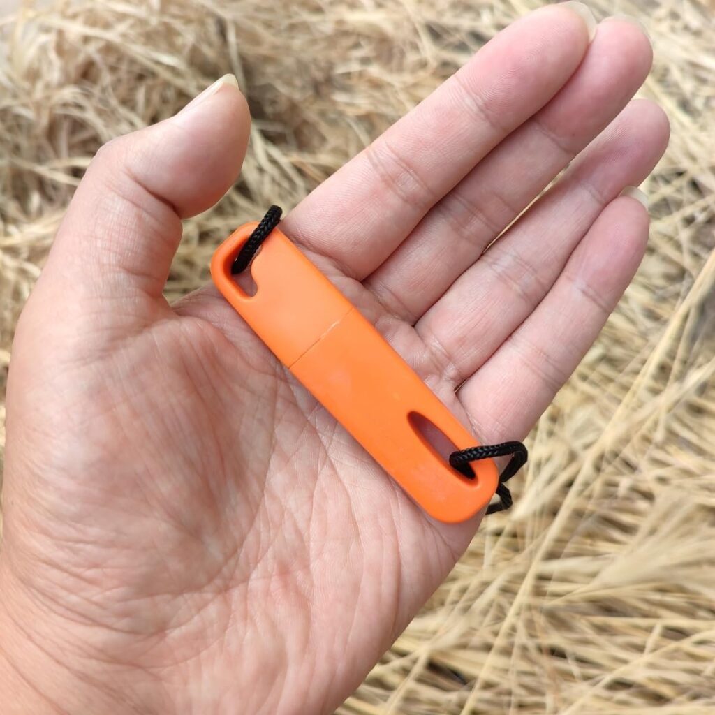 Pocket-sized emergency bulk fire steel with attached black lanyard held in a hand to demonstrate its compact survival gear profile.