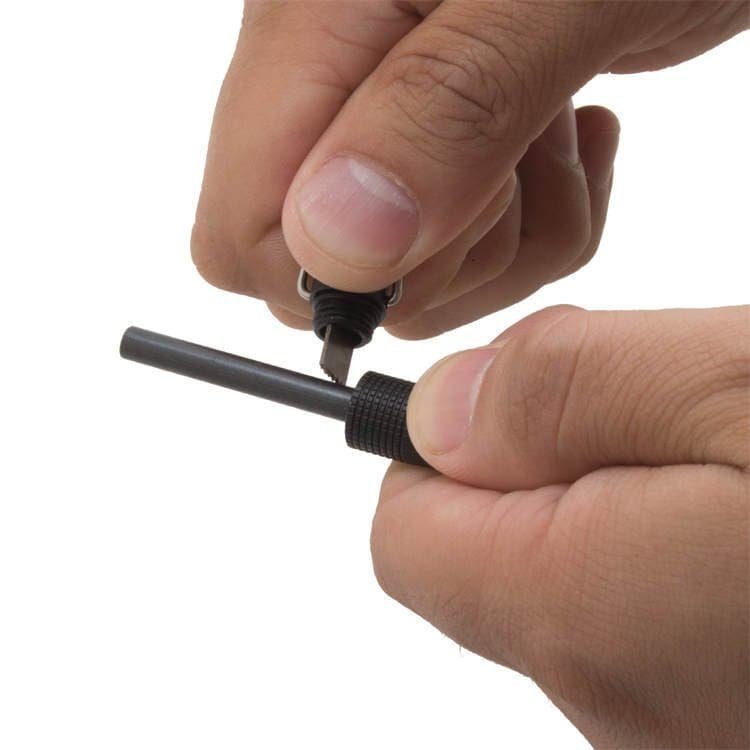 Close-up of hands striking the high-purity ferro rod bulk FRC25 core using the built-in steel scraper to generate 3,000°C spark showers.