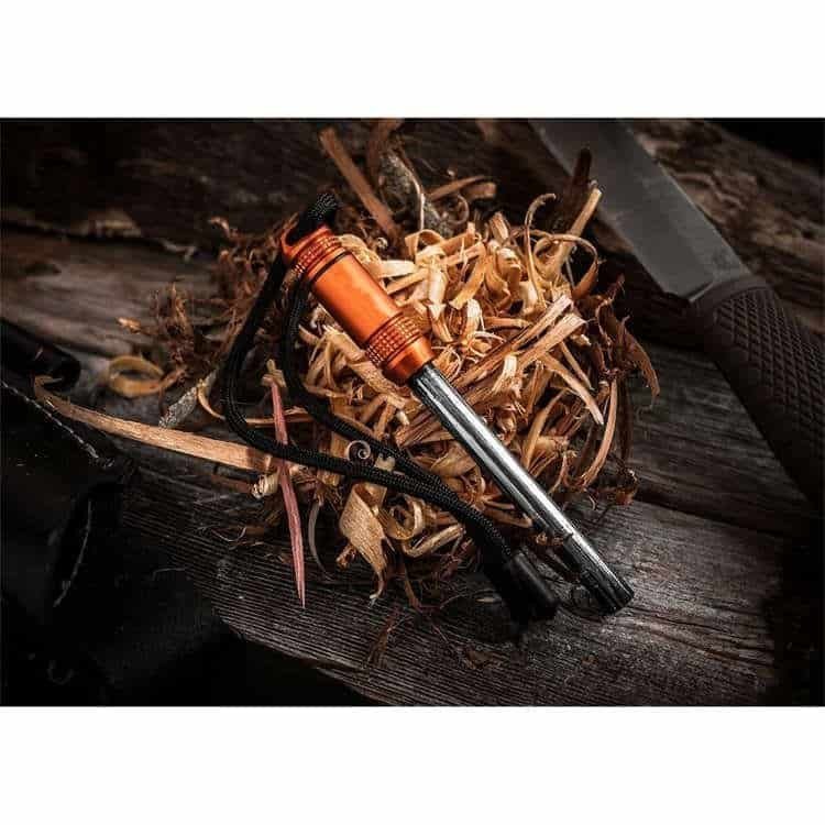 Heavy-duty ferro rod bulk FRC30 placed on dry wood shavings next to a tactical survival knife, demonstrating real-world bushcraft fire preparedness.