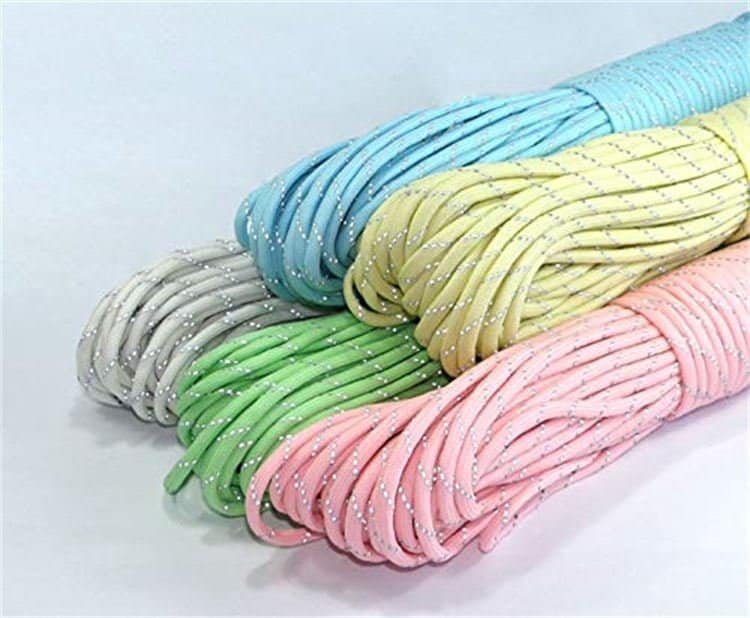 Colorful wholesale paracord bundles in pastel blue, yellow, grey, green, and pink lined up diagonally to display reflective tracer patterns.