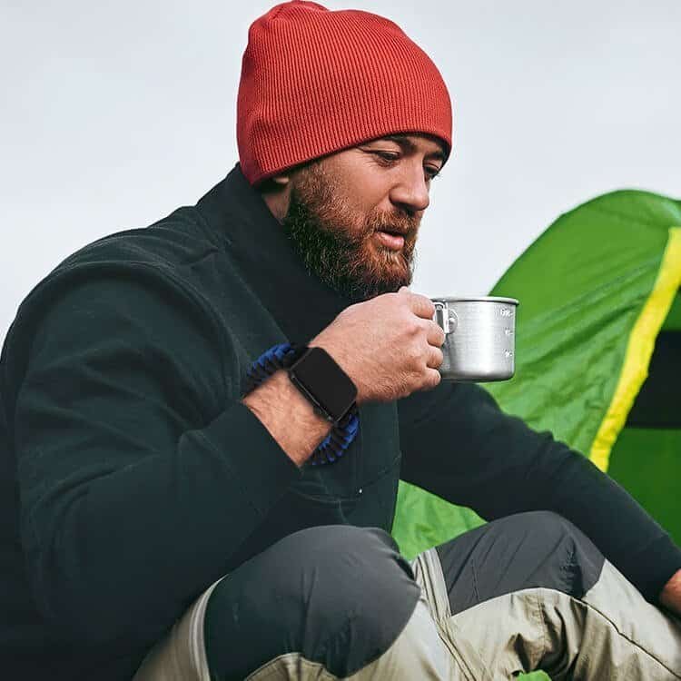 Outdoor camper wearing a tactical smartwatch with a durable braided strap available for paracord watch band bulk orders.