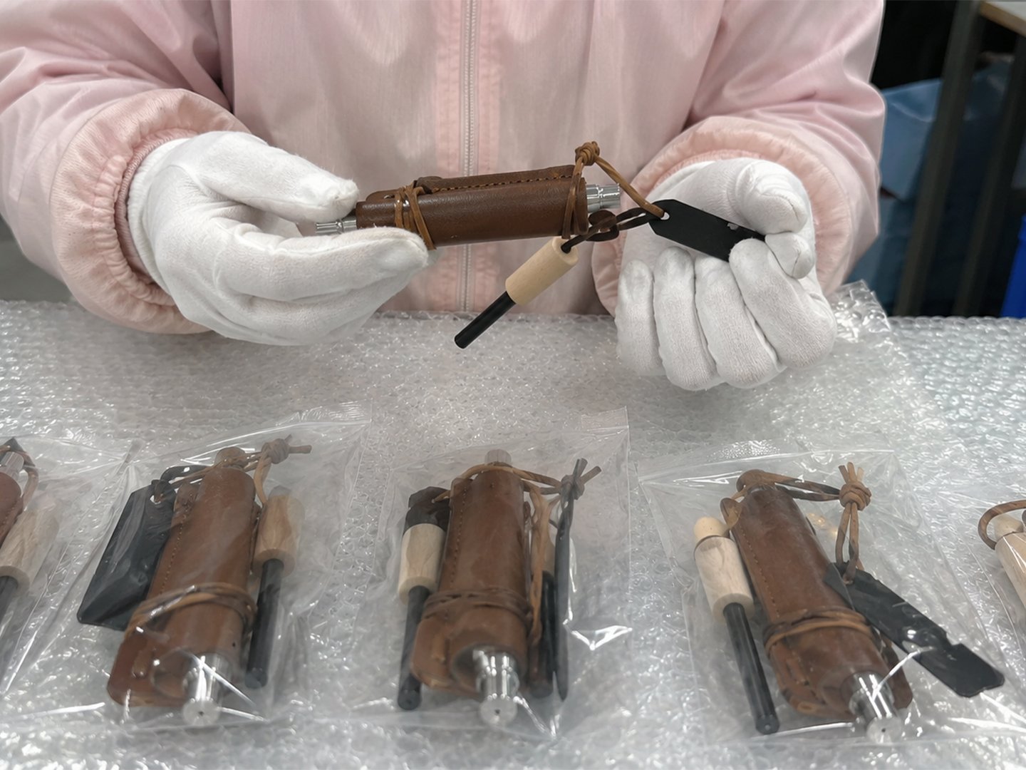 Worker in white gloves inspecting leather-wrapped ferro rod kits