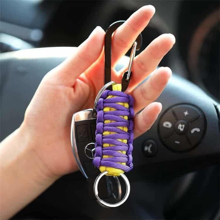 Hand holding a purple PK03 survival paracord keychain with car keys for convenient everyday carry.