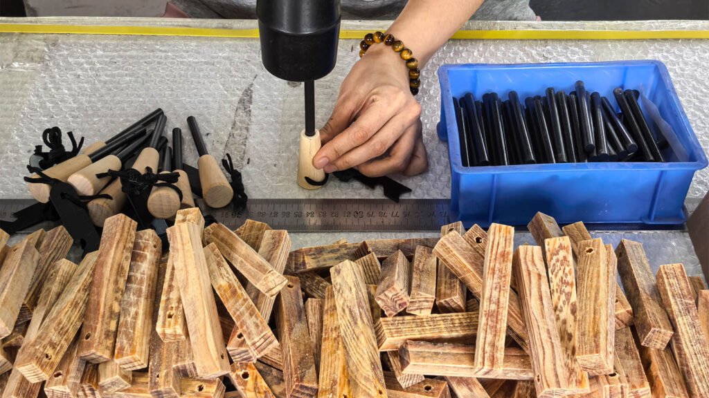 Worker drilling holes in wood handles at the factory