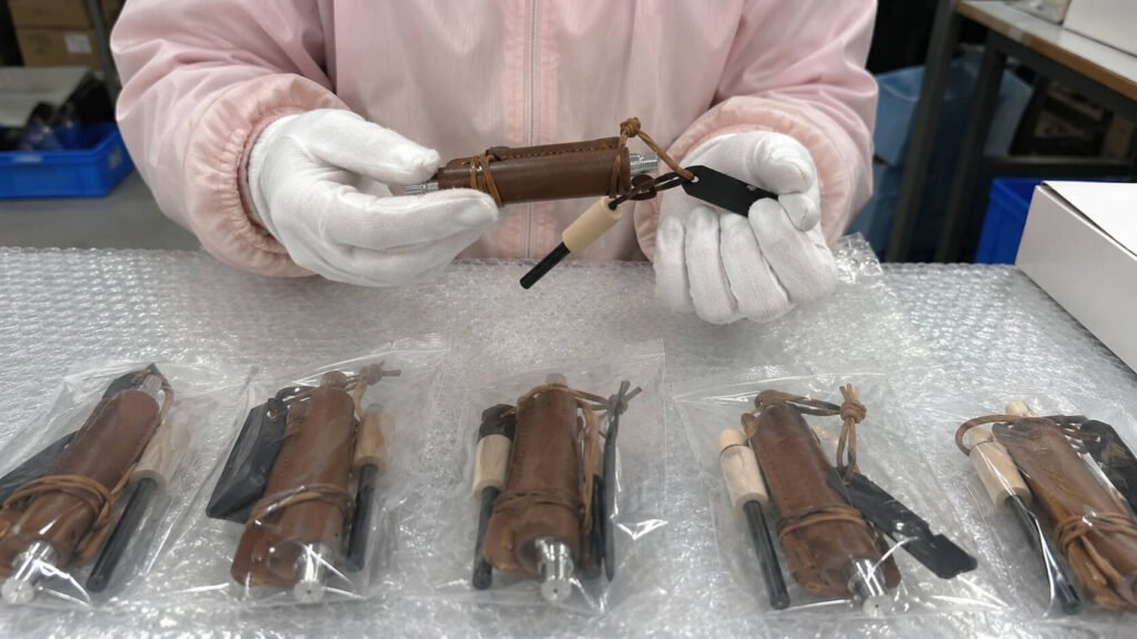 Worker inspecting packaged leather-wrapped ferro rod kits